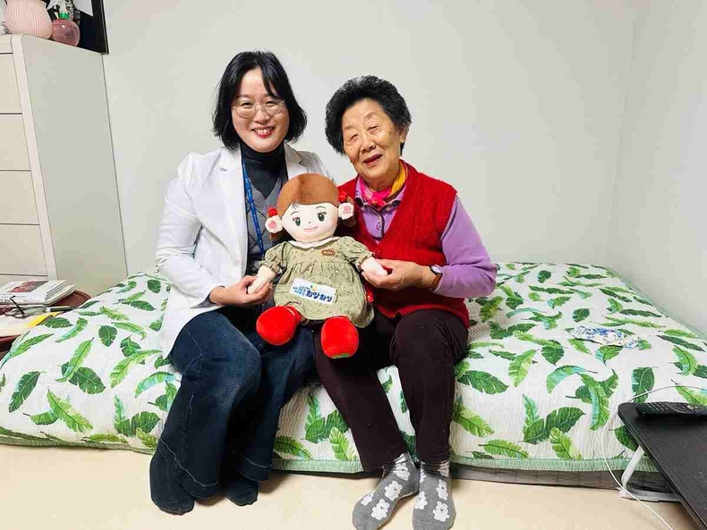 화성시동탄보건소 관계자와 독거 어르신이 AI 돌봄로봇 ‘효돌이’를 함께 들고 환하게 웃고 있다.